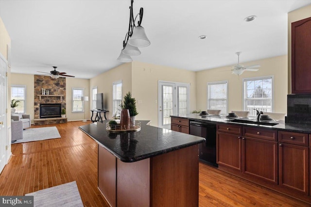 kitchen featuring a kitchen island, hardwood / wood-style floors, a fireplace, black dishwasher, and sink