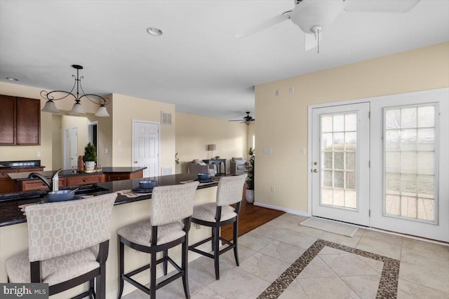 kitchen with light tile patterned flooring, pendant lighting, sink, ceiling fan, and dark brown cabinets