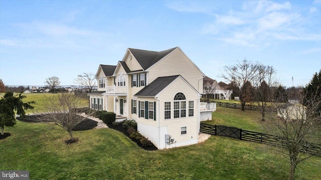 view of side of home featuring a lawn and a balcony