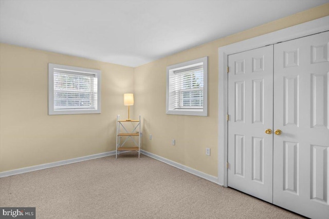 unfurnished bedroom featuring light colored carpet and a closet