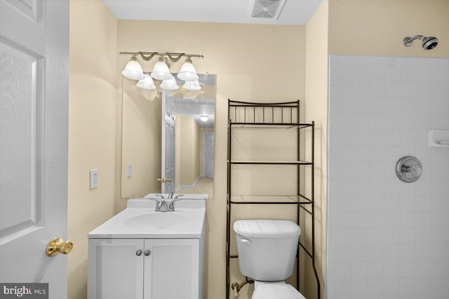 bathroom featuring vanity, toilet, and tiled shower