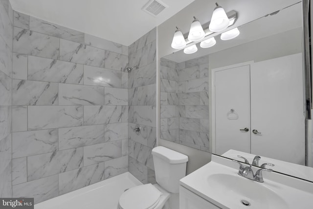 bathroom with tiled shower, vanity, and toilet