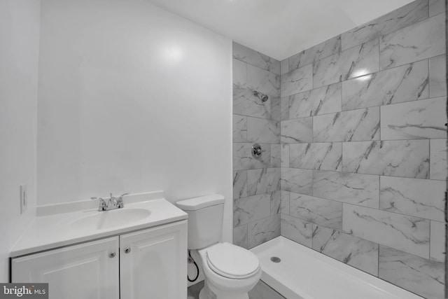 bathroom with vanity, toilet, and tiled shower