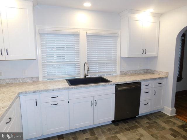 kitchen with white cabinets, sink, light stone countertops, and black dishwasher