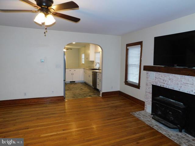 living room featuring ceiling fan, sink, and dark hardwood / wood-style floors