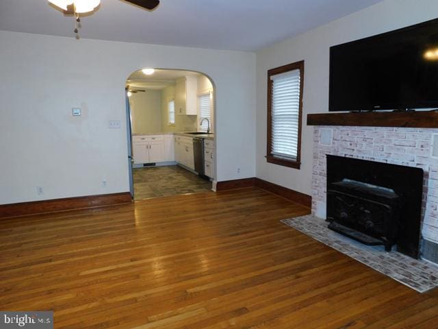 unfurnished living room featuring ceiling fan, sink, and dark wood-type flooring