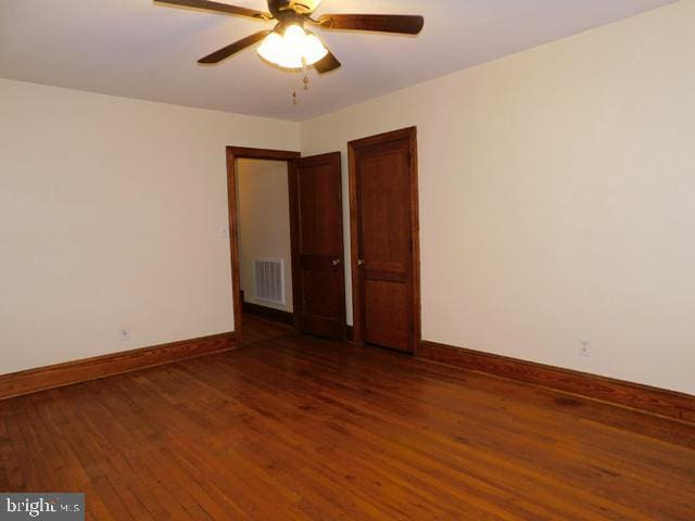 empty room featuring ceiling fan and dark wood-type flooring