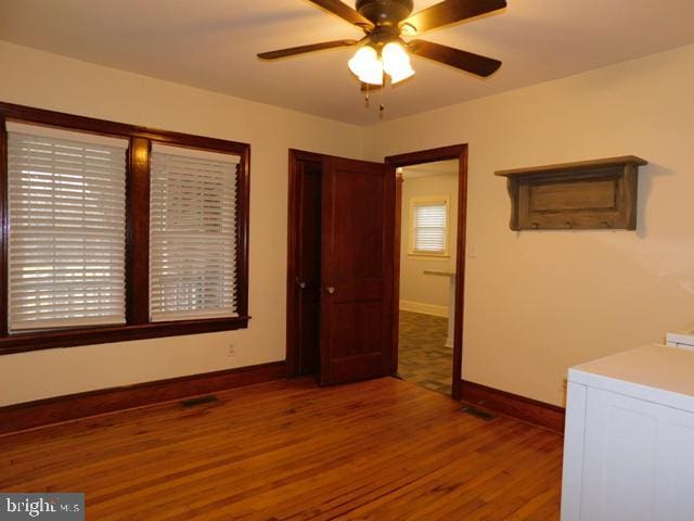 unfurnished bedroom with ceiling fan, hardwood / wood-style floors, and washer / dryer