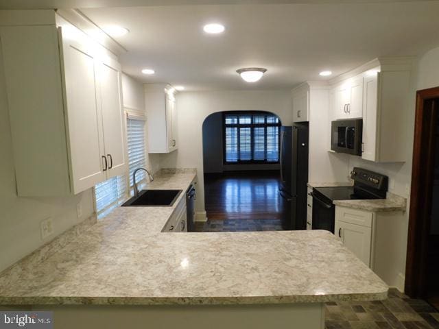 kitchen featuring kitchen peninsula, white cabinetry, sink, and black appliances