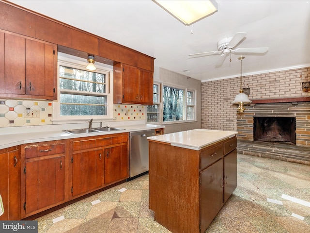 kitchen with stainless steel dishwasher, sink, decorative light fixtures, a fireplace, and a center island