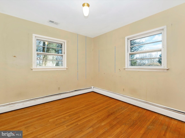 empty room featuring hardwood / wood-style flooring and a baseboard radiator