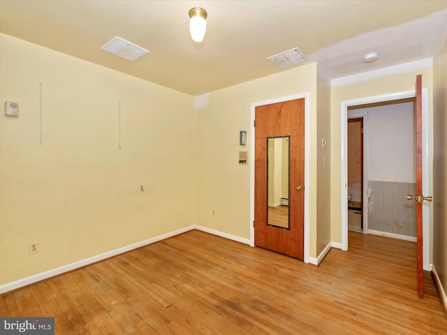 empty room with light hardwood / wood-style floors and a baseboard radiator