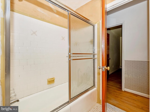 bathroom featuring wood-type flooring and bath / shower combo with glass door