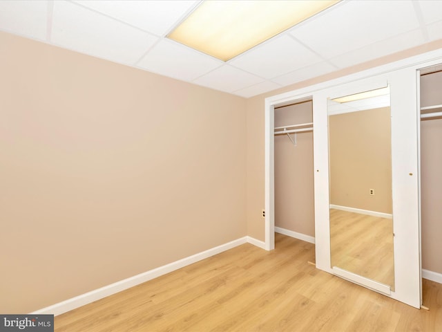 unfurnished bedroom with a drop ceiling and wood-type flooring