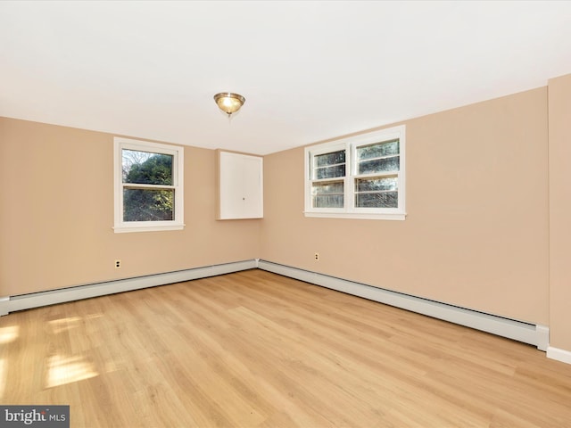 empty room featuring baseboard heating and light hardwood / wood-style floors