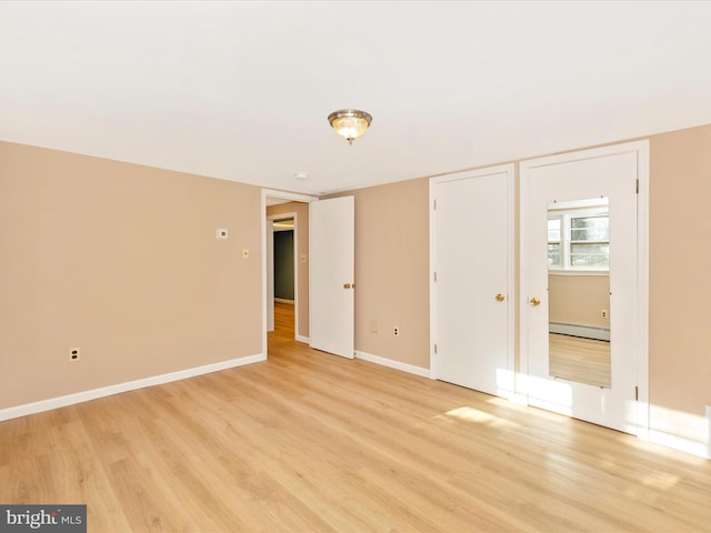 unfurnished room with light hardwood / wood-style flooring and a baseboard heating unit