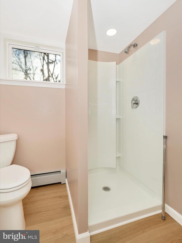 bathroom with toilet, a shower, hardwood / wood-style floors, and a baseboard heating unit