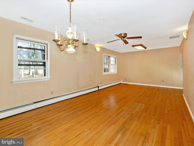 spare room with a baseboard heating unit, a healthy amount of sunlight, ceiling fan with notable chandelier, and light hardwood / wood-style floors