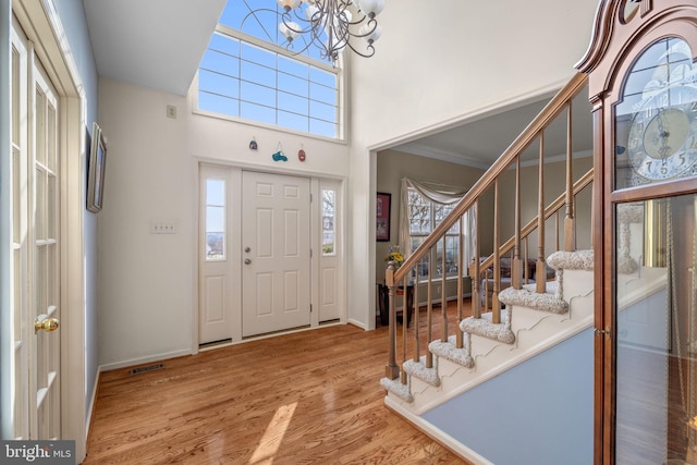 entrance foyer with a wealth of natural light, wood-type flooring, and an inviting chandelier