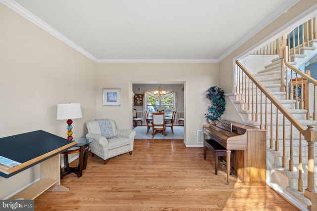 sitting room with light wood-type flooring, ornamental molding, and a notable chandelier