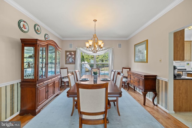 dining space with ornamental molding, light hardwood / wood-style floors, and a notable chandelier