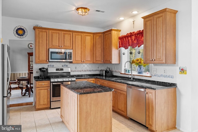 kitchen with dark stone counters, a center island, light tile patterned floors, and stainless steel appliances