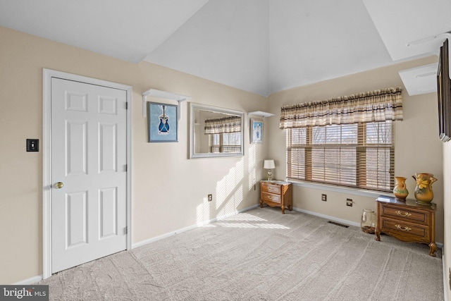 unfurnished bedroom featuring light colored carpet and high vaulted ceiling