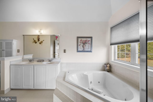 bathroom with tile patterned flooring, vanity, and tiled tub