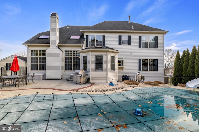 rear view of property featuring a patio and a covered pool