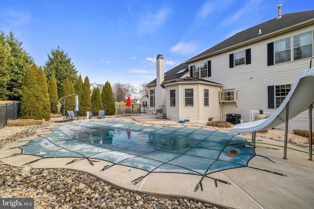 view of swimming pool with cooling unit, a patio area, and a water slide