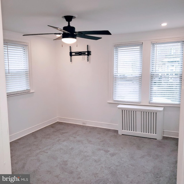 spare room with radiator, light carpet, and ceiling fan