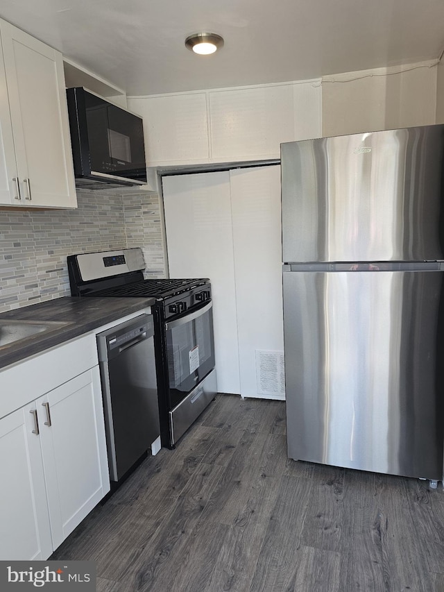 kitchen with decorative backsplash, appliances with stainless steel finishes, dark wood-type flooring, sink, and white cabinets