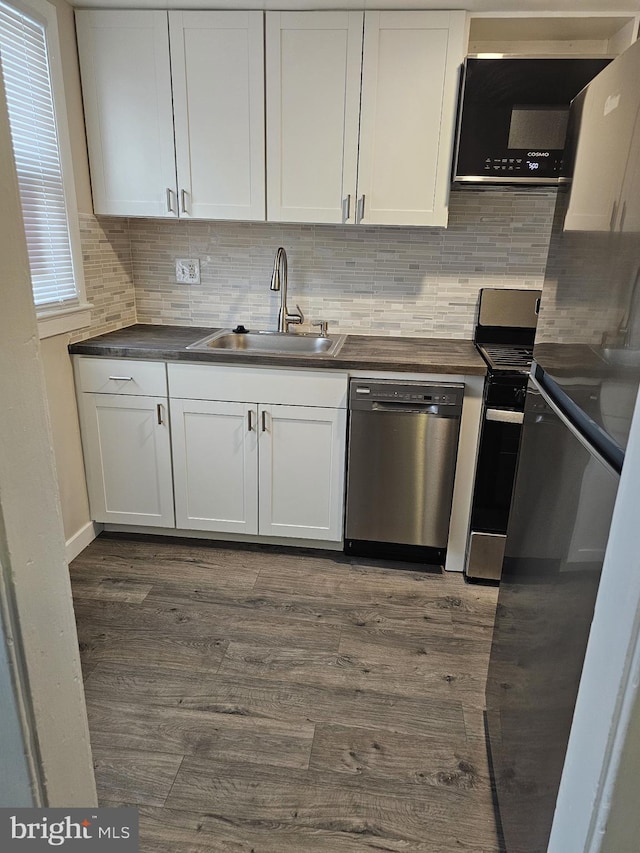 kitchen with white cabinets, appliances with stainless steel finishes, dark hardwood / wood-style flooring, and sink