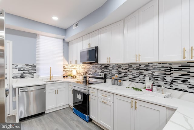 kitchen featuring white cabinetry, sink, light stone counters, and appliances with stainless steel finishes