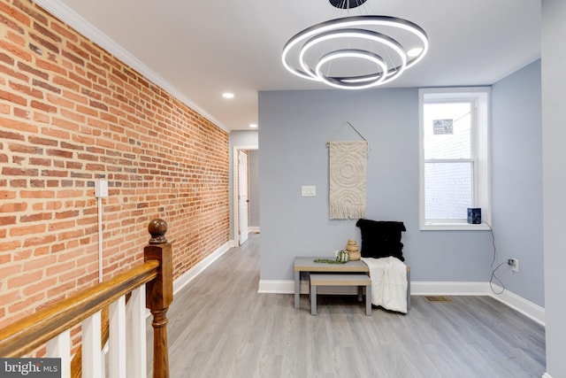 sitting room featuring light hardwood / wood-style floors, plenty of natural light, and brick wall