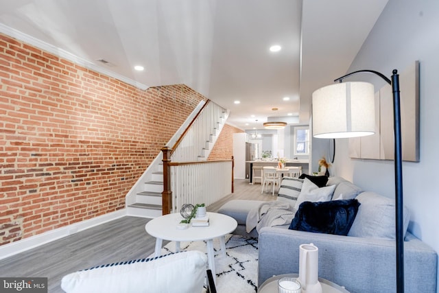 living room featuring light hardwood / wood-style floors, ornamental molding, and brick wall