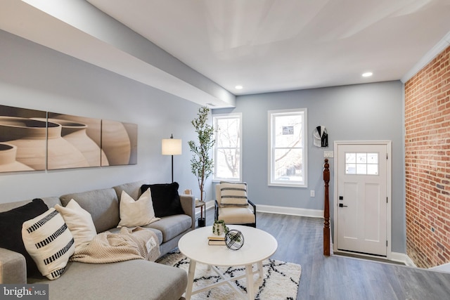 living room featuring a wealth of natural light, brick wall, and hardwood / wood-style flooring