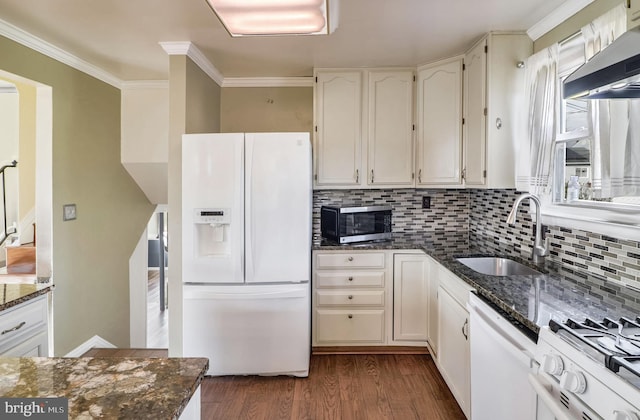 kitchen with sink, range hood, dark stone counters, white appliances, and decorative backsplash