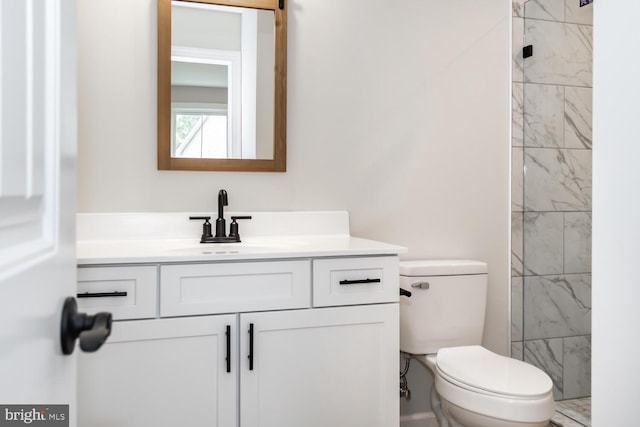 bathroom with tiled shower, vanity, and toilet