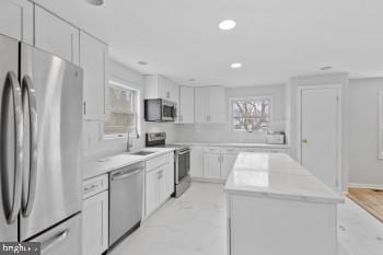 kitchen featuring white cabinets, a kitchen island, sink, and stainless steel appliances