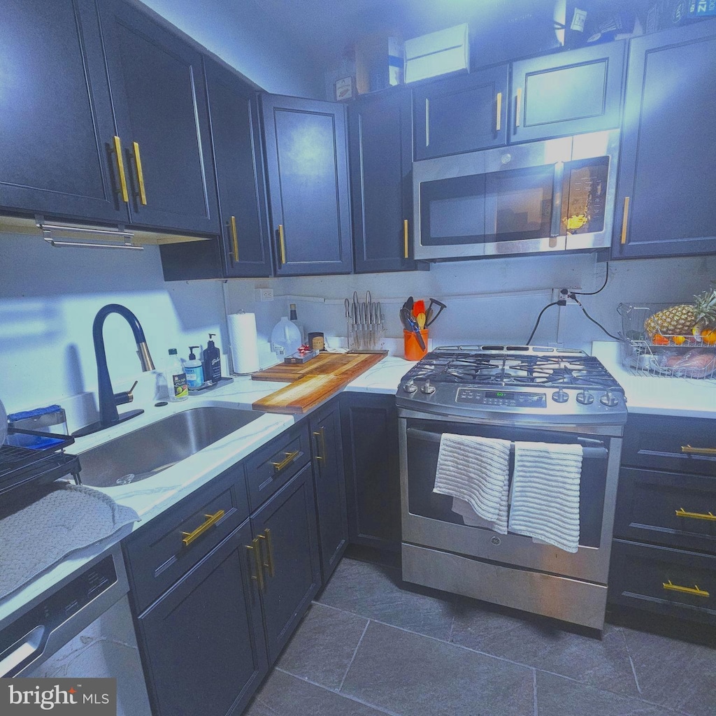 kitchen with dark tile patterned flooring, sink, and stainless steel appliances