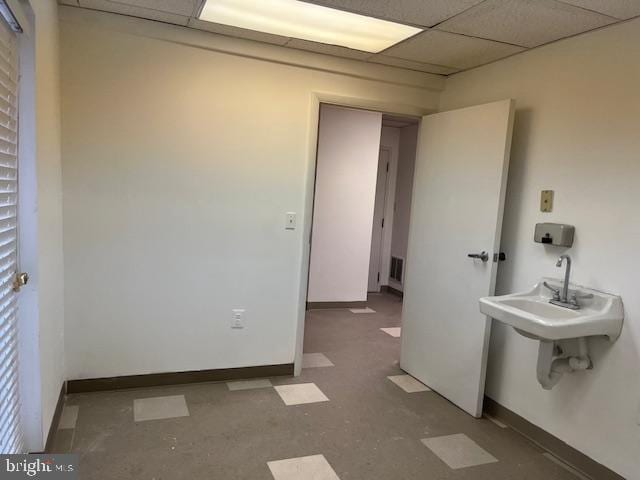 bathroom with concrete flooring and a drop ceiling