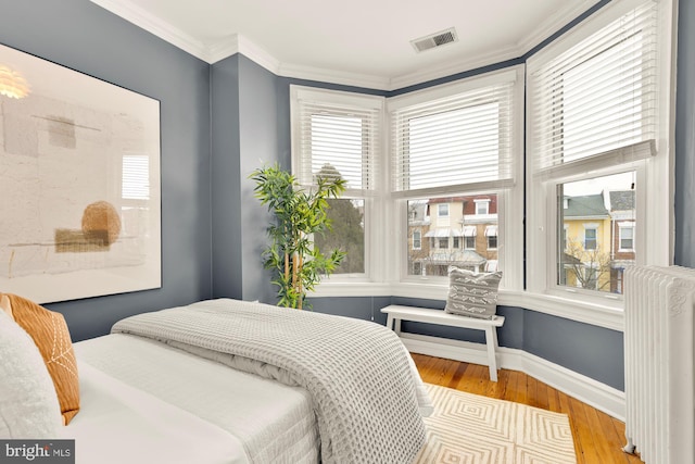 bedroom with ornamental molding, light hardwood / wood-style flooring, and radiator