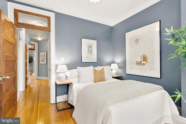 bedroom with crown molding and light hardwood / wood-style floors