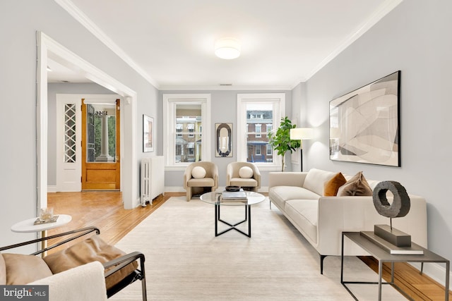 living room with radiator heating unit, light hardwood / wood-style flooring, and ornamental molding