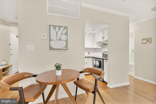 dining space with light hardwood / wood-style flooring and ornamental molding