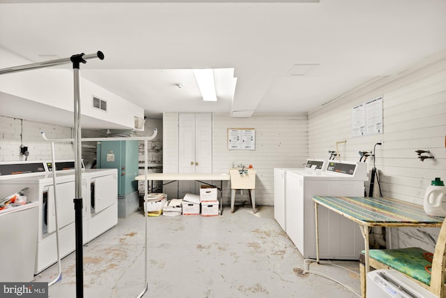 clothes washing area with independent washer and dryer and wood walls