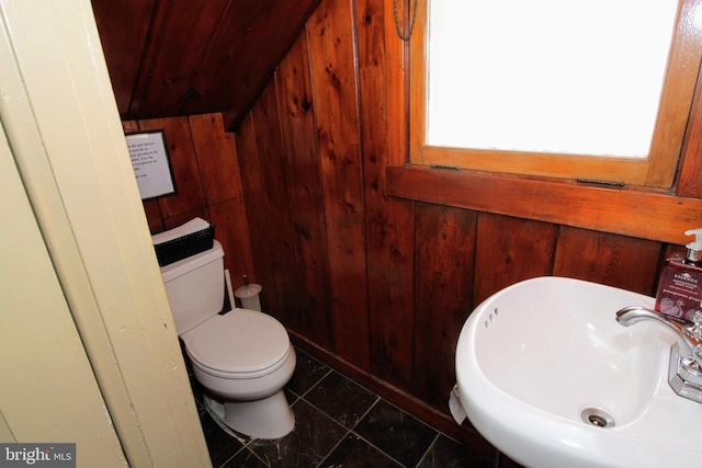 bathroom featuring tile patterned floors, wood walls, sink, and toilet