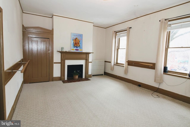 unfurnished living room with carpet flooring, radiator heating unit, and a wealth of natural light