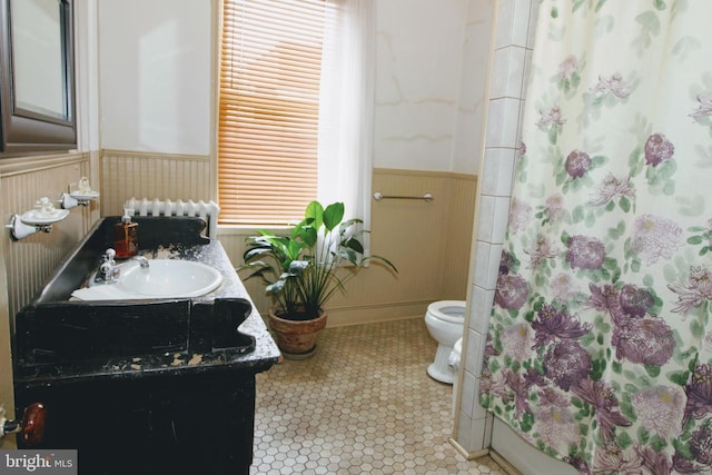 bathroom with radiator, curtained shower, vanity, and toilet